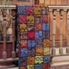 A mosaic Ralli Quilt hanging from a wooden railing